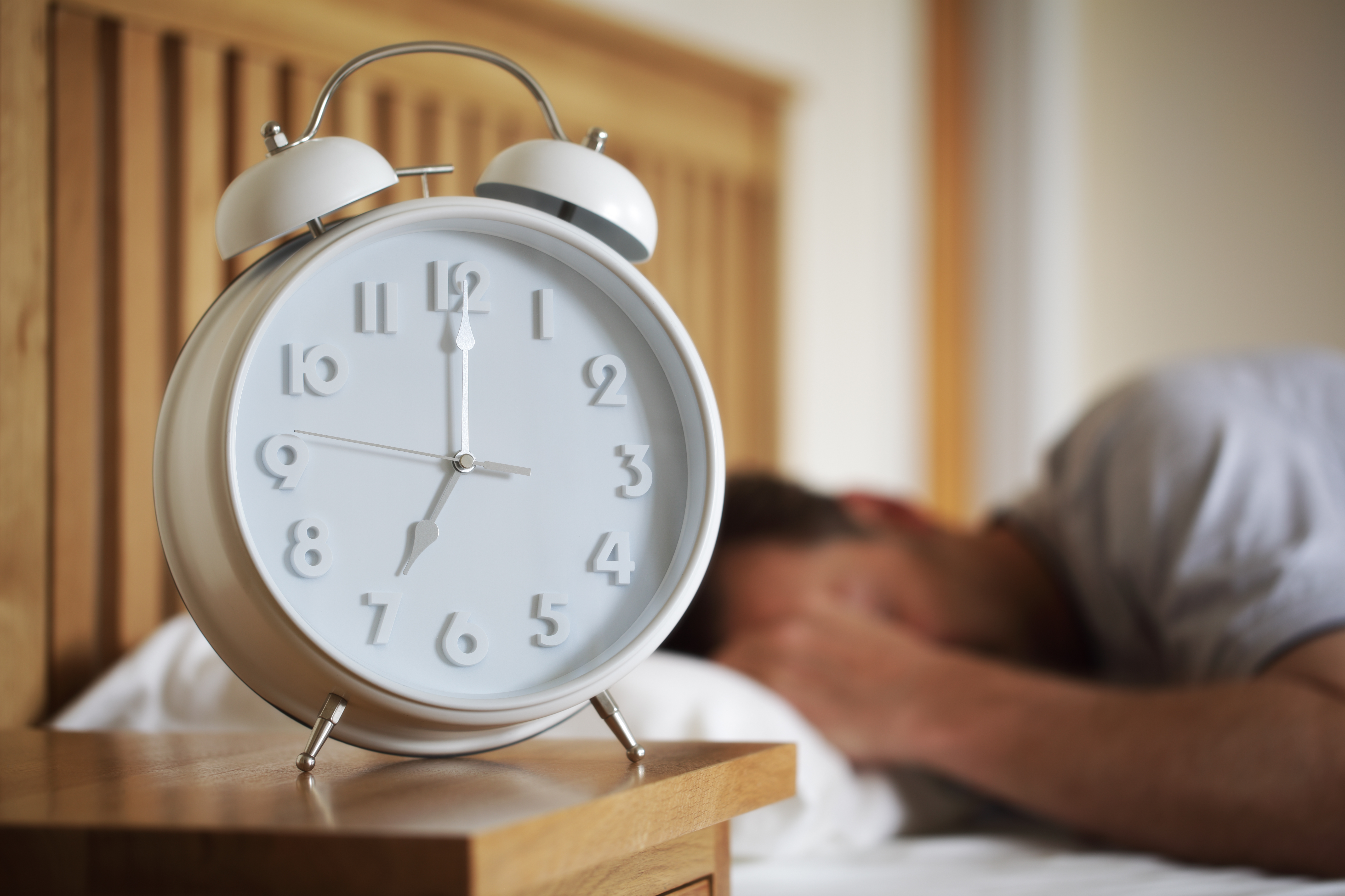 Man sleeping with alarm clock foreground concept for morning, ti