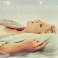 A woman laying in her bed in her robe looking up at the sky