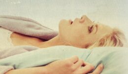 A woman laying in her bed in her robe looking up at the sky