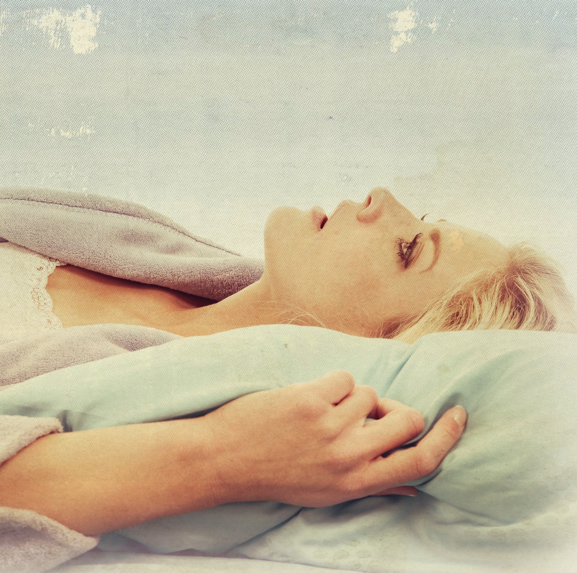 A woman laying in her bed in her robe looking up at the sky