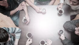 Creative Setting: Students sitting around table drinking coffee in college cafe