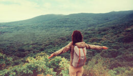 Traveler Girl Standing With Raised Arms On Mountain