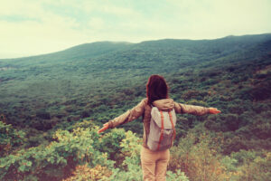 Traveler Girl Standing With Raised Arms On Mountain